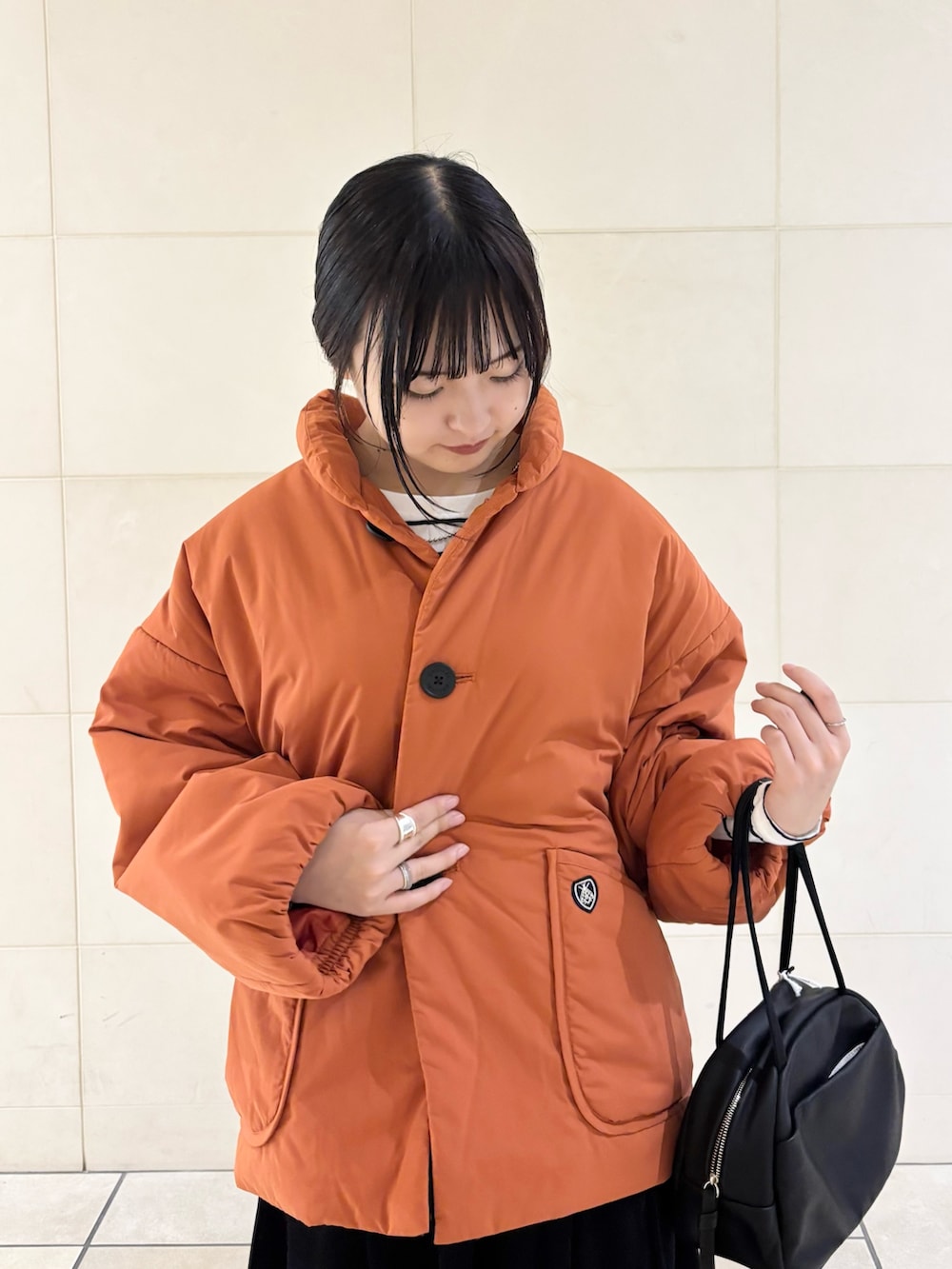 オレンジ系のブルゾン、グレー系のスカート、ブラック系のボストンバッグを着用したレディースの秋コーディネートの5枚目の写真