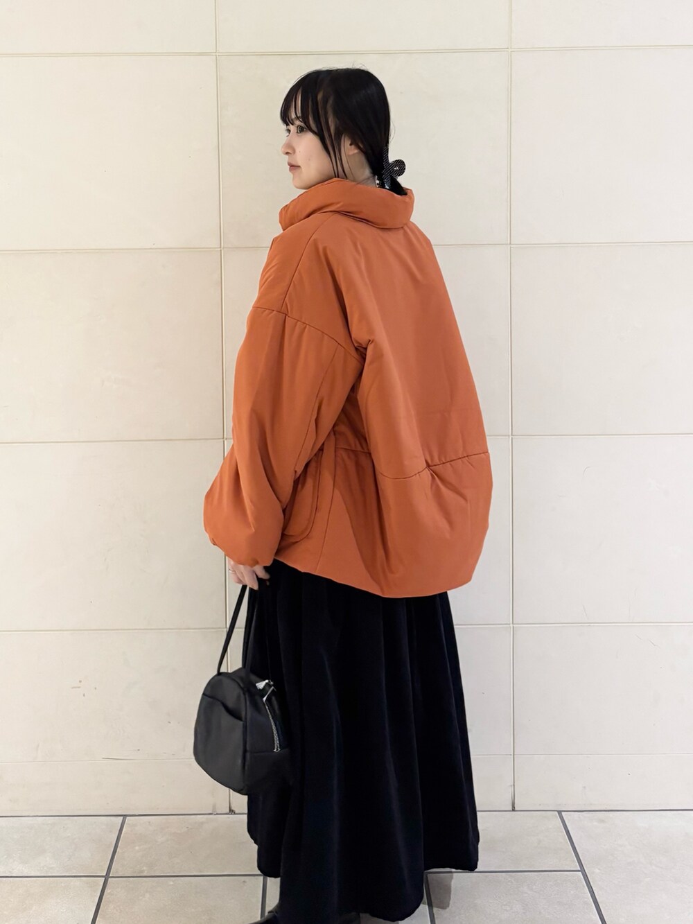 オレンジ系のブルゾン、グレー系のスカート、ブラック系のボストンバッグを着用したレディースの秋コーディネートの3枚目の写真