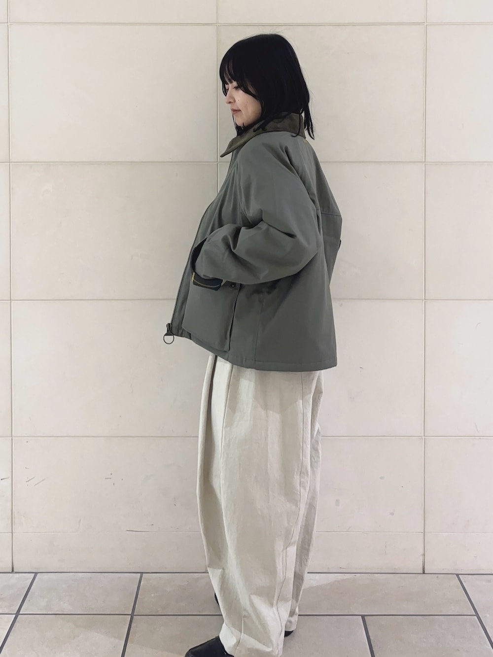 レッド系のニット/セーター、グリーン系のブルゾン、ホワイト系のその他パンツを着用したレディースの冬コーディネートの3枚目の写真