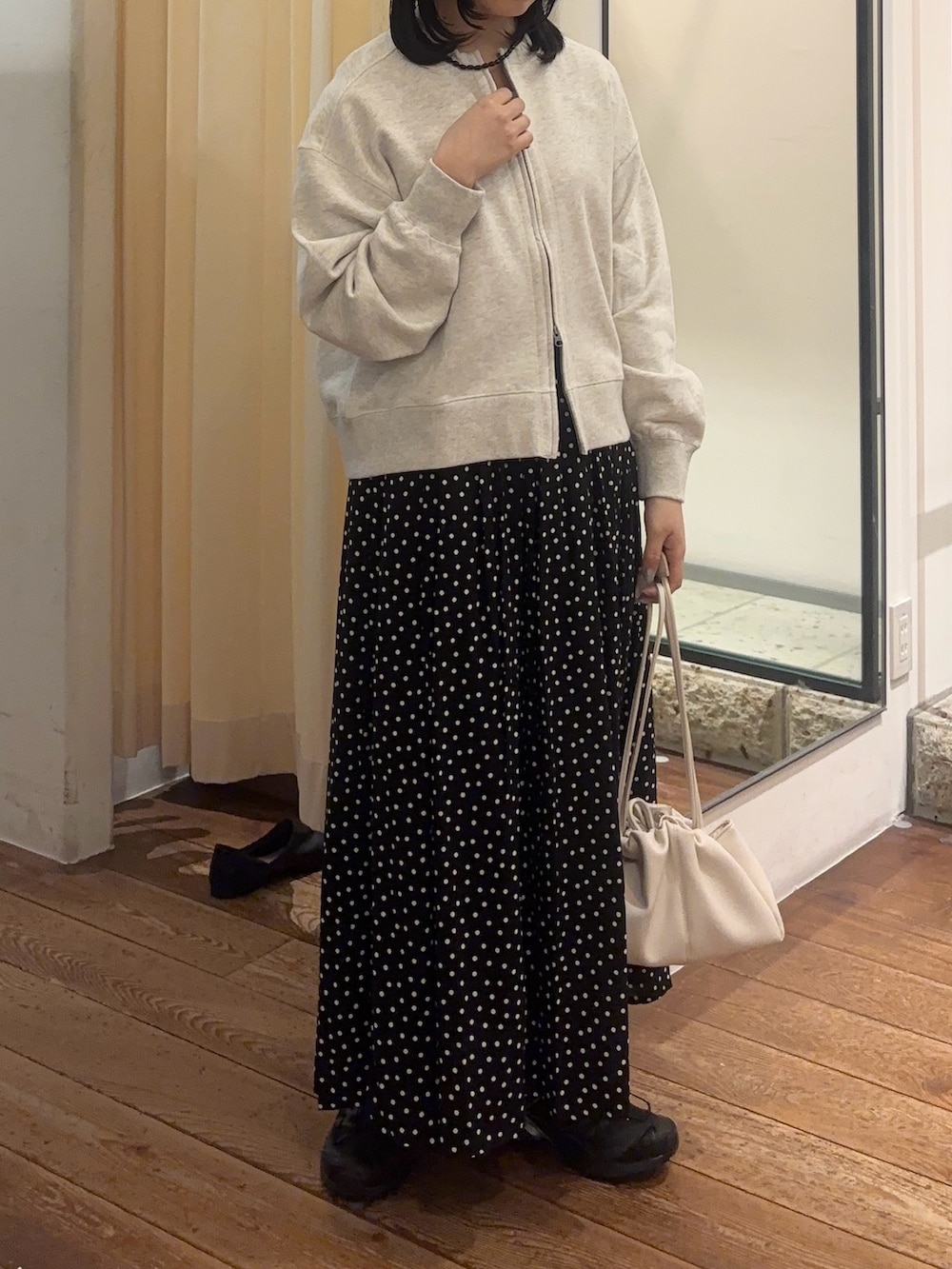 ブラック系のスカート、ホワイト系のショルダーバッグ、ブラック系のスニーカーを着用したレディースの春コーディネートの2枚目の写真