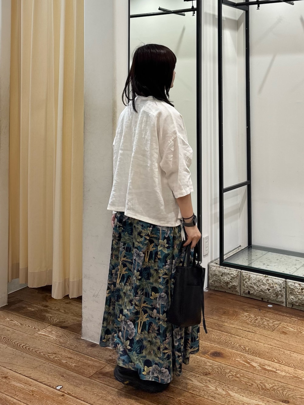 ホワイト系のシャツ/ブラウス、ブルー系のスカート、ブラック系のトートバッグを着用したレディースの夏コーディネートの3枚目の写真