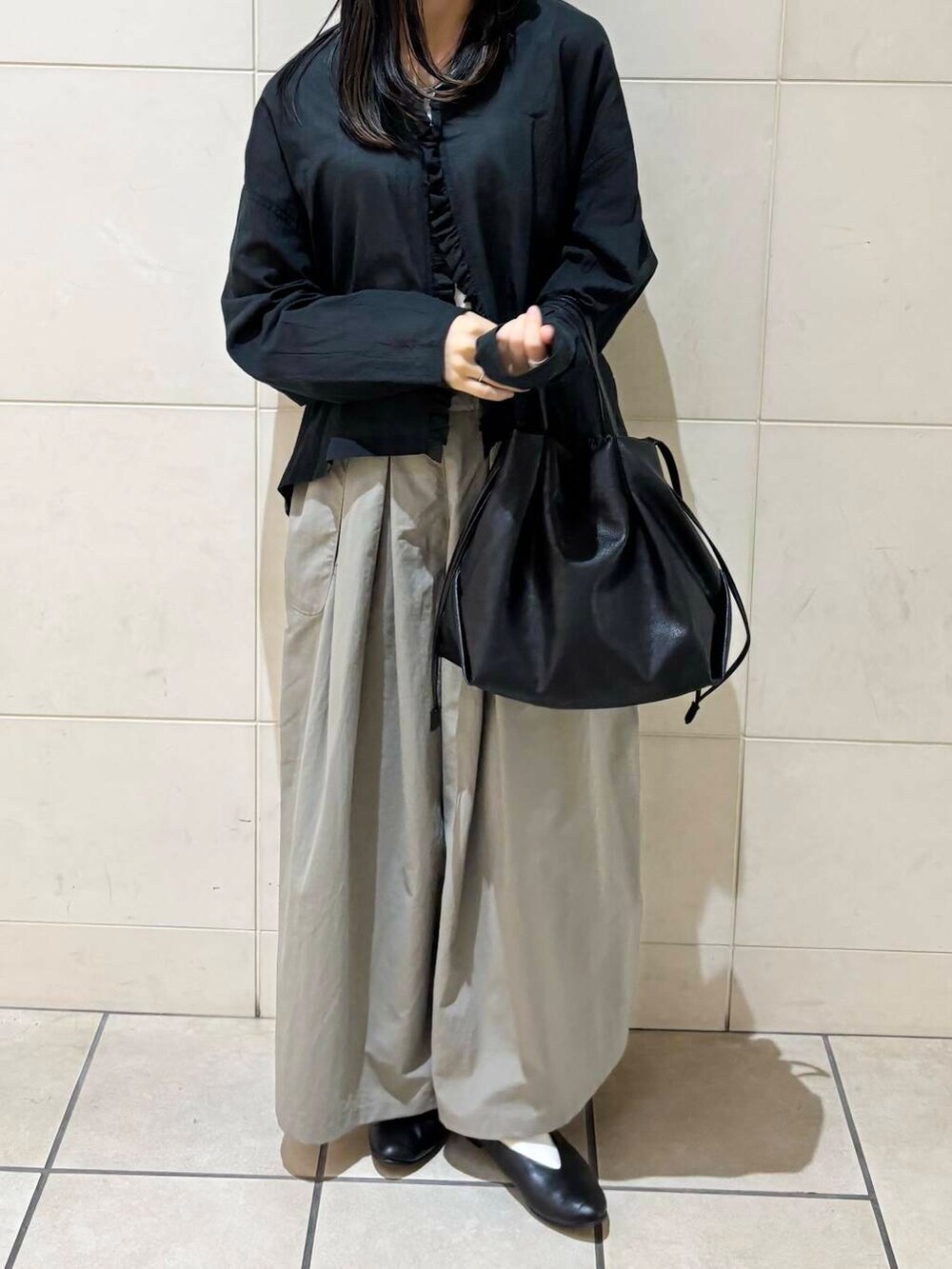 ブラック系のパンプス、ブラック系のショルダーバッグ、ホワイト系のタンクトップを着用したレディースの夏コーディネートの2枚目の写真