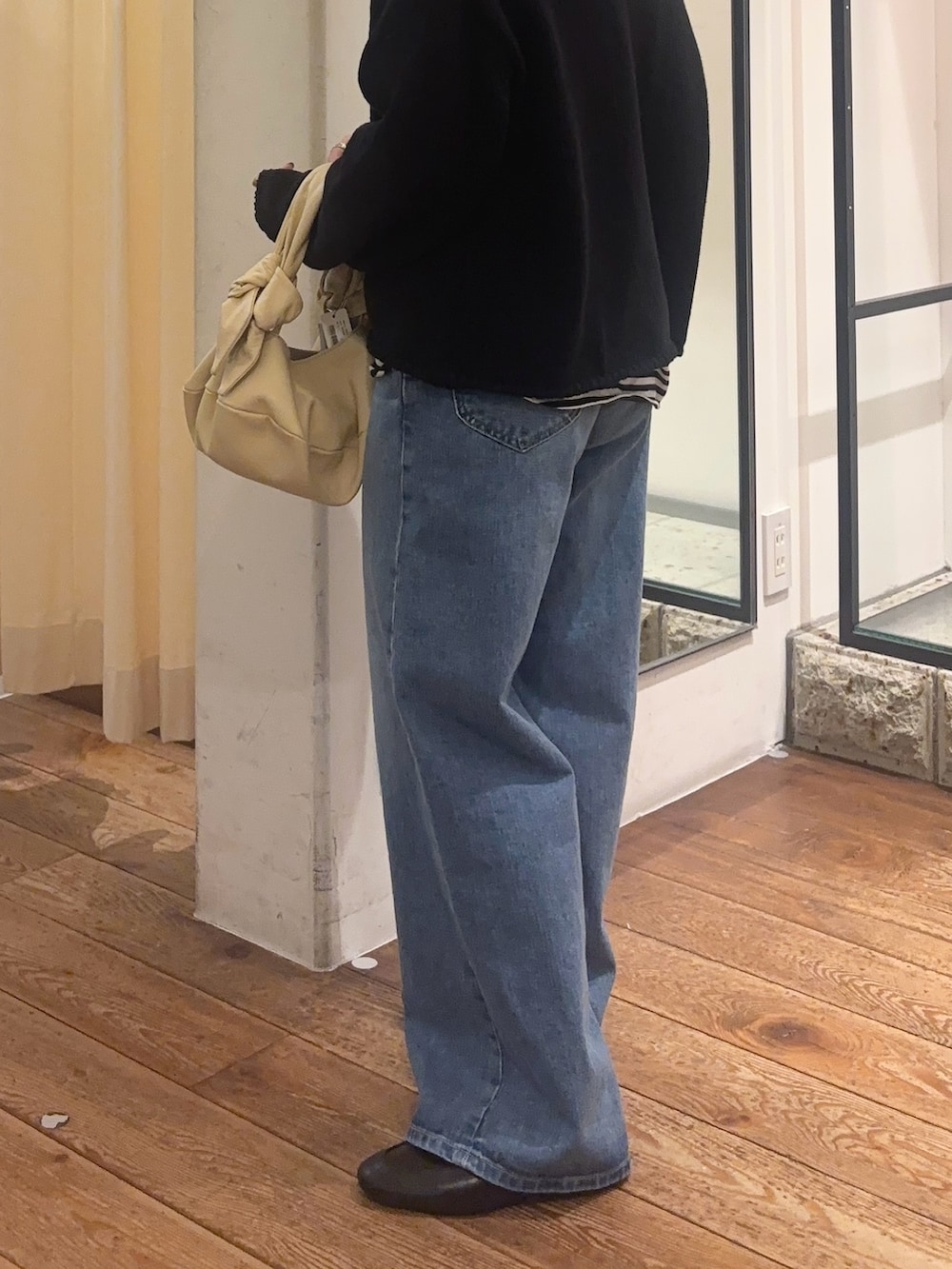 ブルー系のデニムパンツ、ブラック系のローファー、ベージュ系のハンドバッグを着用したレディースの冬コーディネートの4枚目の写真