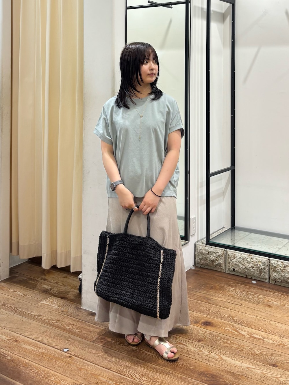 ゴールド系のサンダル、ブラック系のトートバッグ、ベージュ系のスカートを着用したレディースの夏コーディネートの2枚目の写真