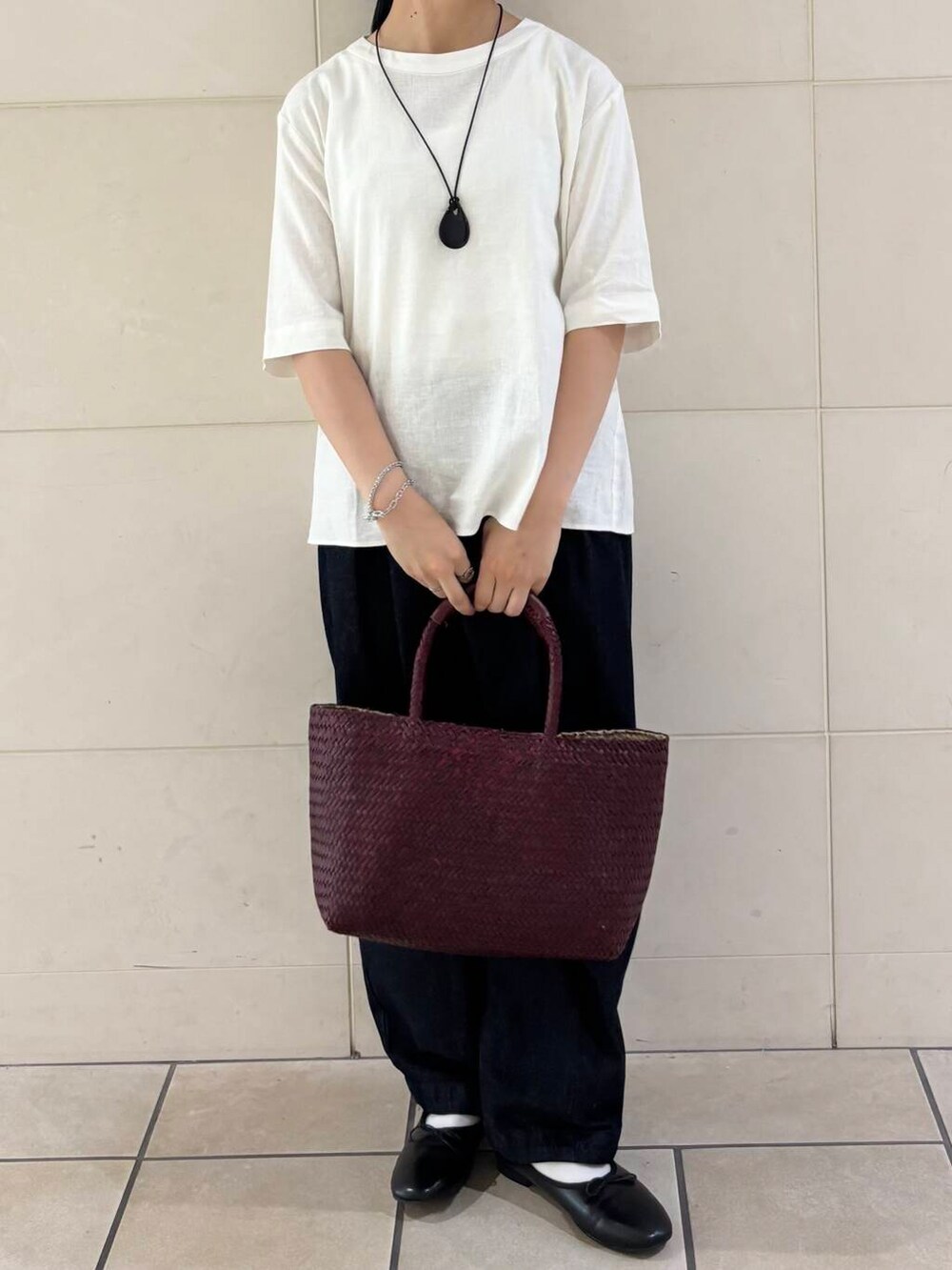 レッド系のトートバッグ、ブラック系のバレエシューズ、ホワイト系のシャツ/ブラウスを着用したレディースの夏コーディネートの2枚目の写真