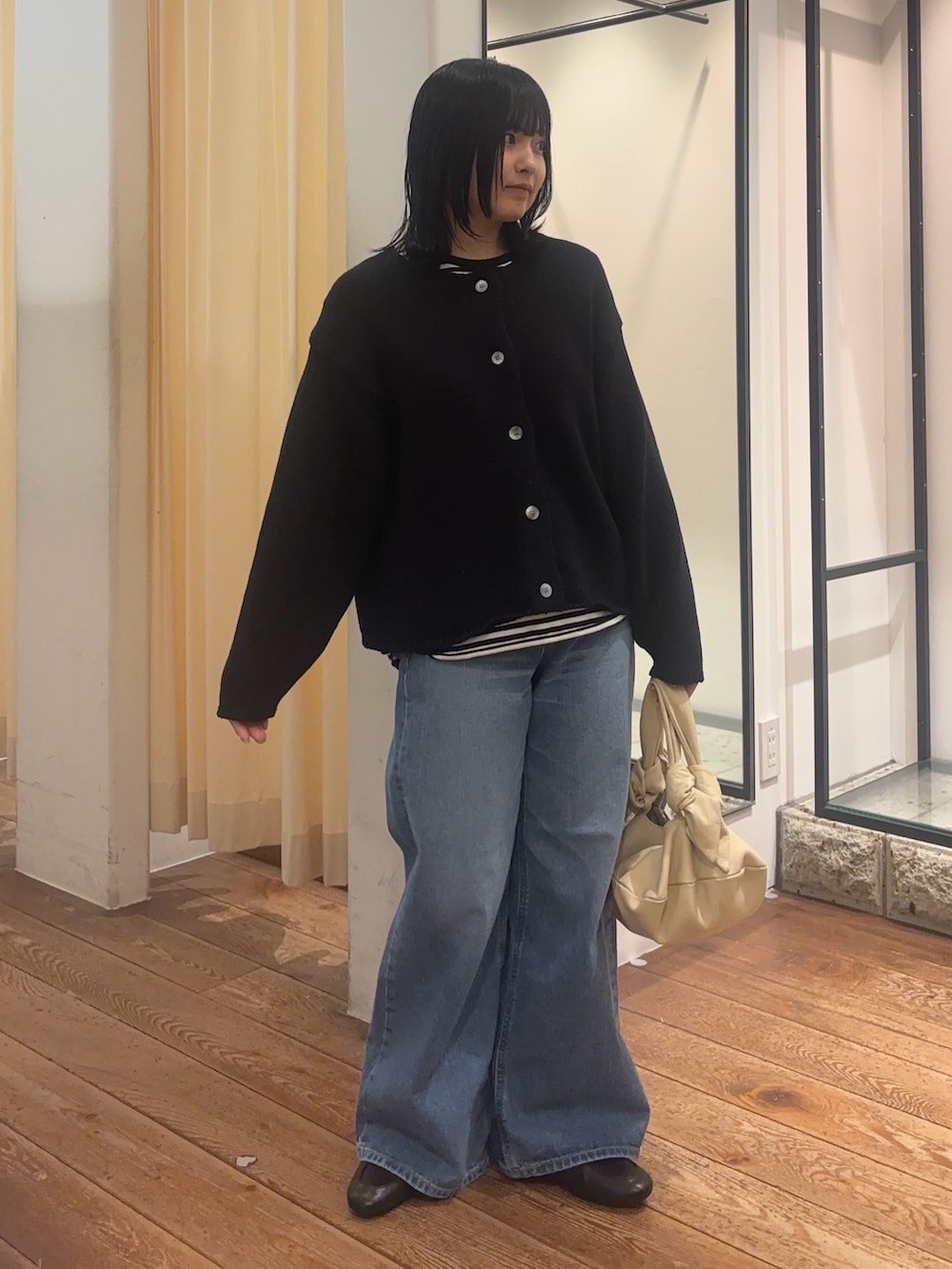 ブルー系のデニムパンツ、ブラック系のローファー、ベージュ系のハンドバッグを着用したレディースの冬コーディネートの2枚目の写真