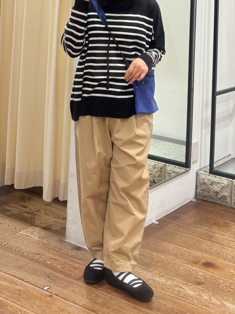 ベージュ系のその他パンツ、ブルー系のショルダーバッグ、ブラック系のニット/セーターを着用したレディースの夏コーディネートの5枚目の写真
