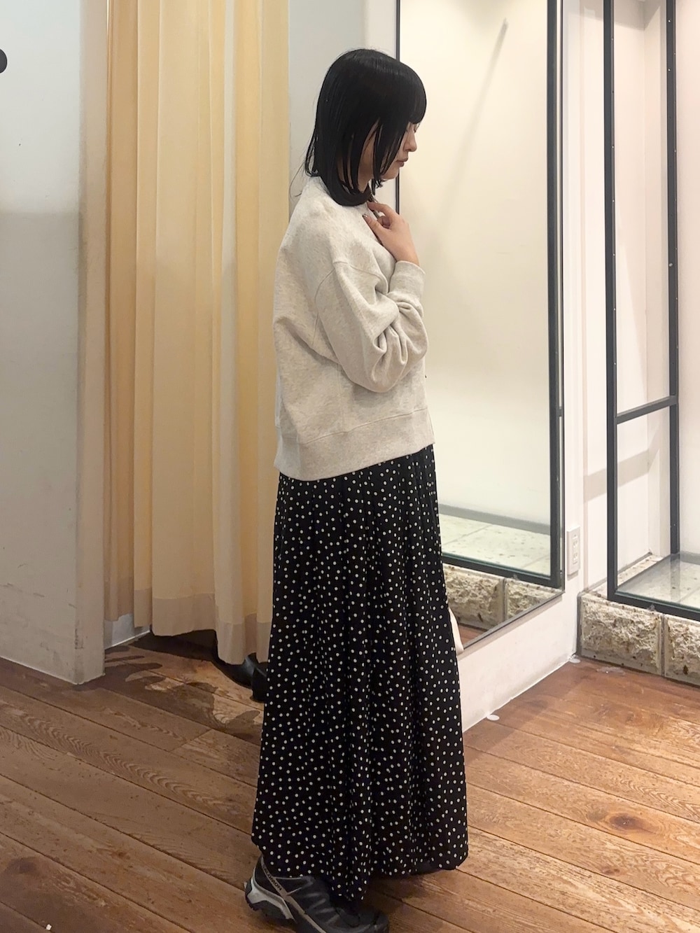 ブラック系のスカート、ホワイト系のショルダーバッグ、ブラック系のスニーカーを着用したレディースの春コーディネートの3枚目の写真