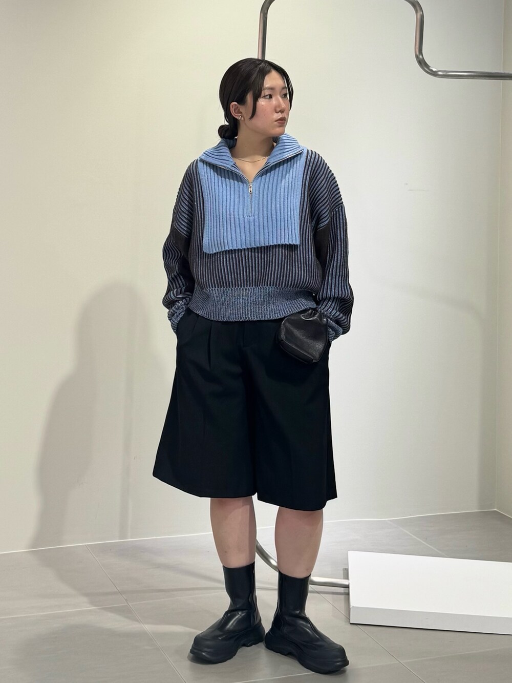 ブラック系のブーツ、ブラック系のショルダーバッグ、グレー系のニット/セーターを着用したレディースの秋コーディネートの2枚目の写真