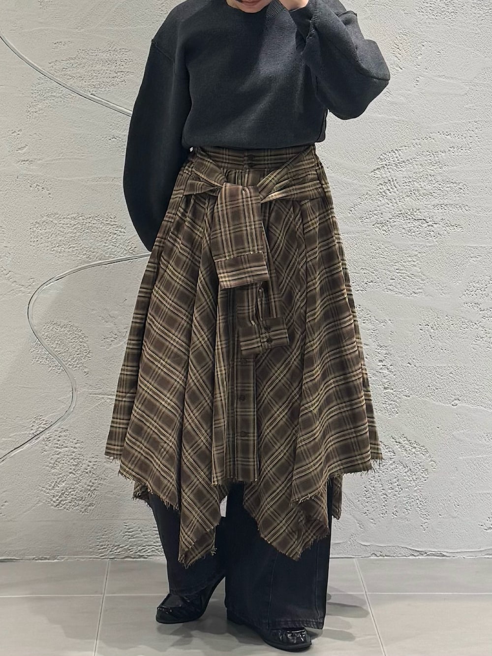 ブラック系のデニムパンツ、ブラウン系のスカート、グレー系のニット/セーターを着用したレディースの秋コーディネートの3枚目の写真