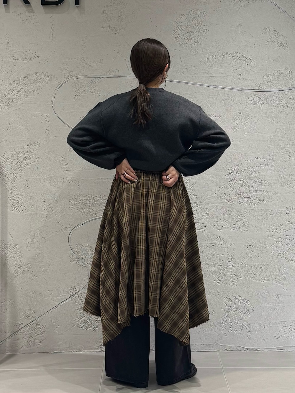 ブラック系のデニムパンツ、ブラウン系のスカート、グレー系のニット/セーターを着用したレディースの秋コーディネートの8枚目の写真