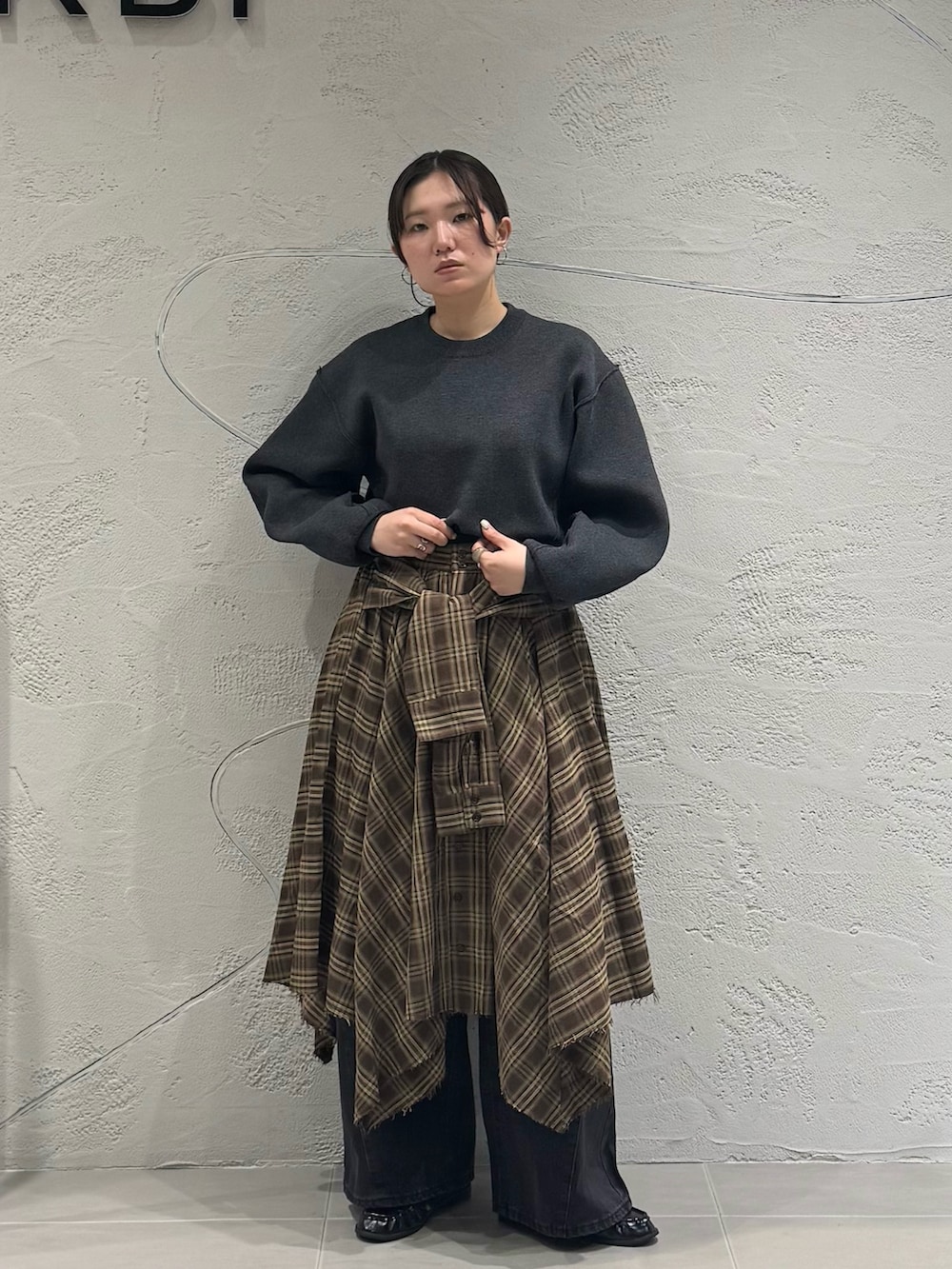 ブラック系のデニムパンツ、ブラウン系のスカート、グレー系のニット/セーターを着用したレディースの秋コーディネートの5枚目の写真