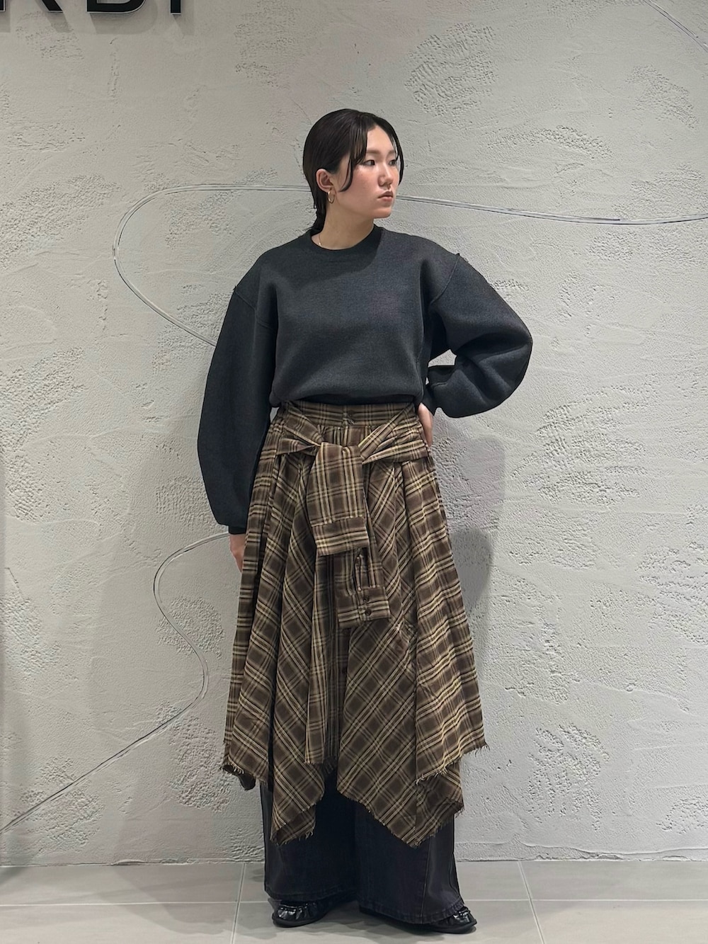 ブラック系のデニムパンツ、ブラウン系のスカート、グレー系のニット/セーターを着用したレディースの秋コーディネートの4枚目の写真