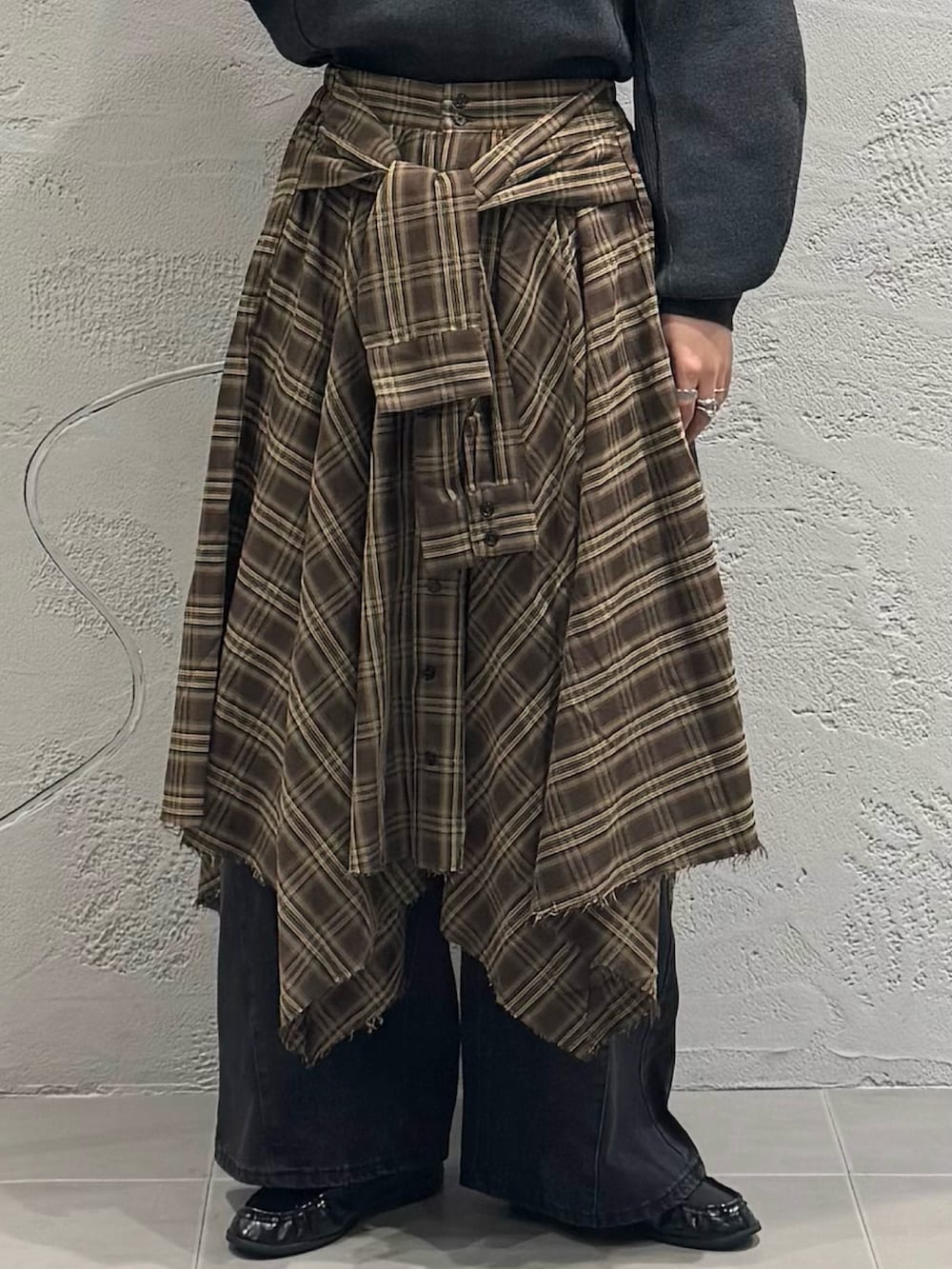 ブラック系のデニムパンツ、ブラウン系のスカート、グレー系のニット/セーターを着用したレディースの秋コーディネートの6枚目の写真