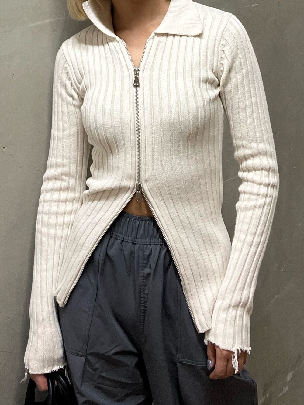 ホワイト系のニット/セーター、グレー系のその他パンツ、ブラック系のハンドバッグを着用したレディースの春コーディネートの4枚目の写真