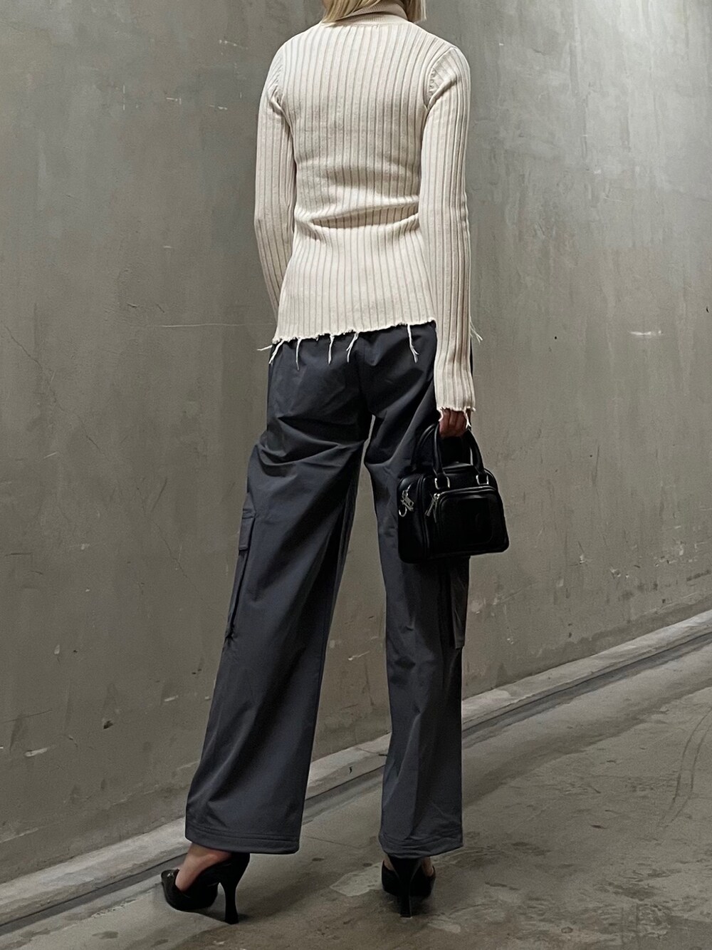 ホワイト系のニット/セーター、グレー系のその他パンツ、ブラック系のハンドバッグを着用したレディースの春コーディネートの2枚目の写真