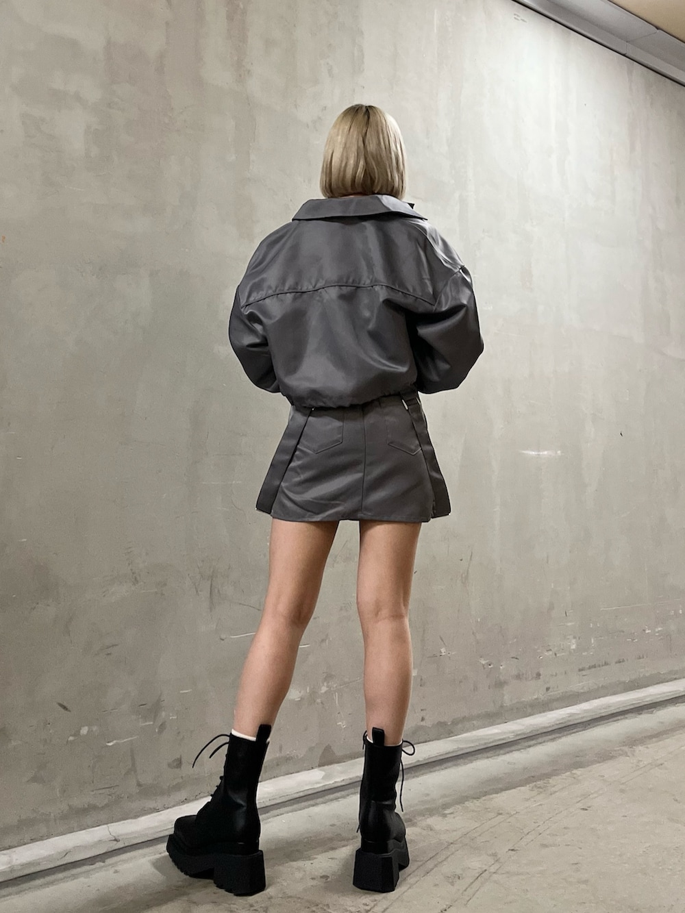 グレー系のブルゾン、グレー系のスカート、ホワイト系のニット/セーターを着用したレディースの冬コーディネートの2枚目の写真