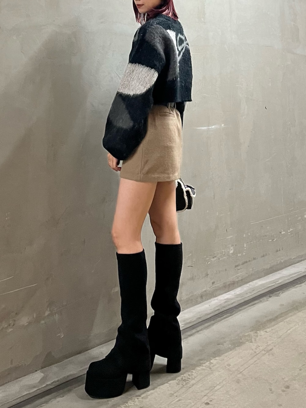 ブラック系のニット/セーター、ベージュ系のスカート、ブラック系のハンドバッグを着用したレディースの秋コーディネートの3枚目の写真