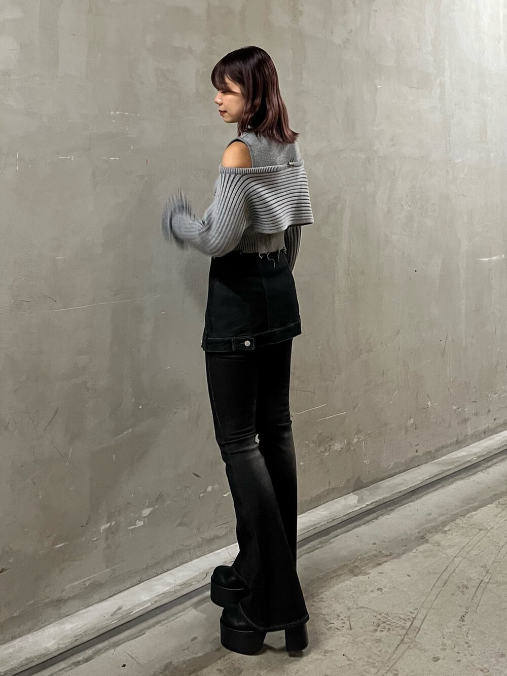 グレー系のニット/セーター、ブラック系のデニムパンツ、ブラック系のブーツを着用したレディースの秋コーディネートの2枚目の写真
