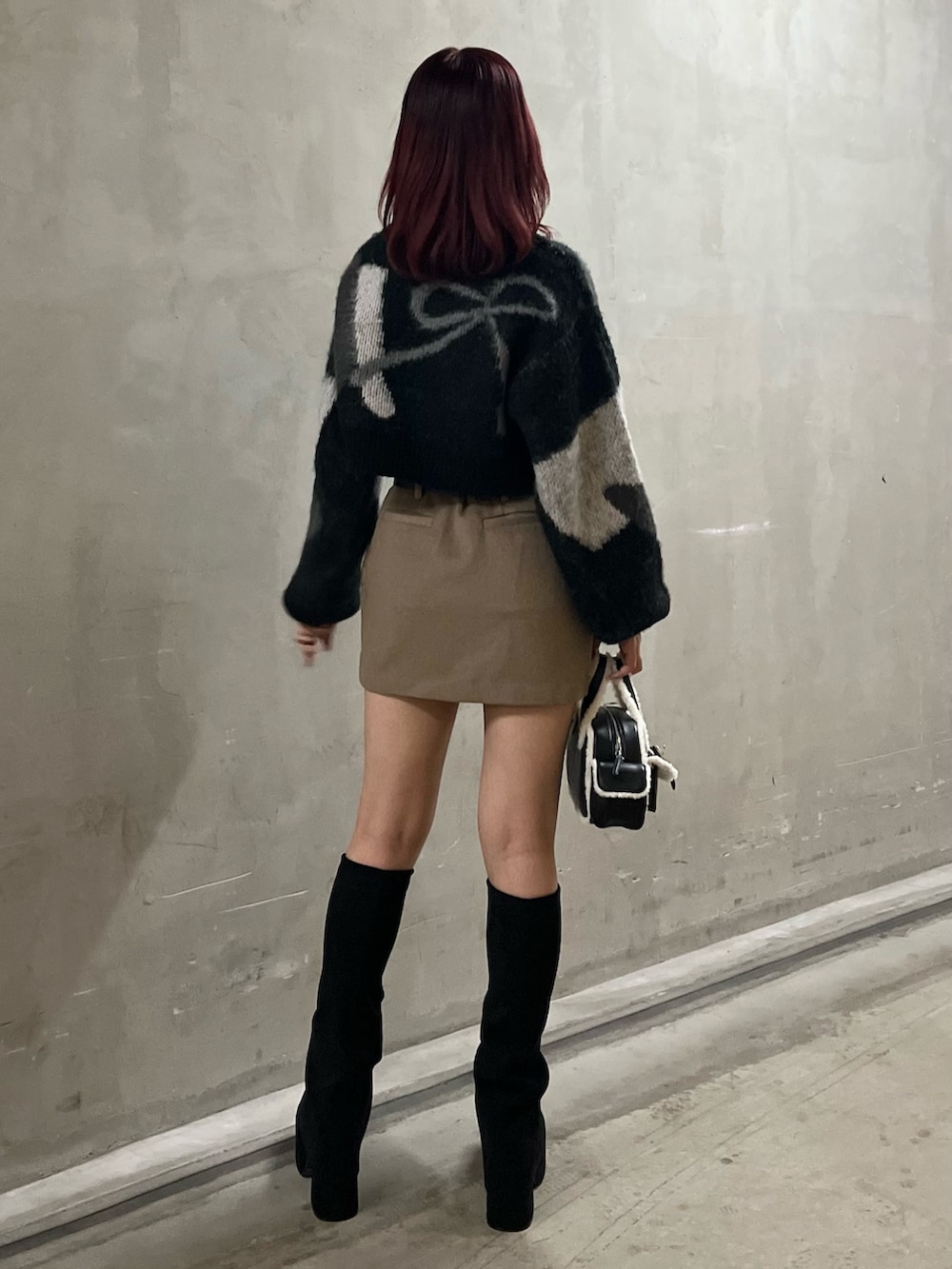 ブラック系のニット/セーター、ベージュ系のスカート、ブラック系のハンドバッグを着用したレディースの秋コーディネートの2枚目の写真