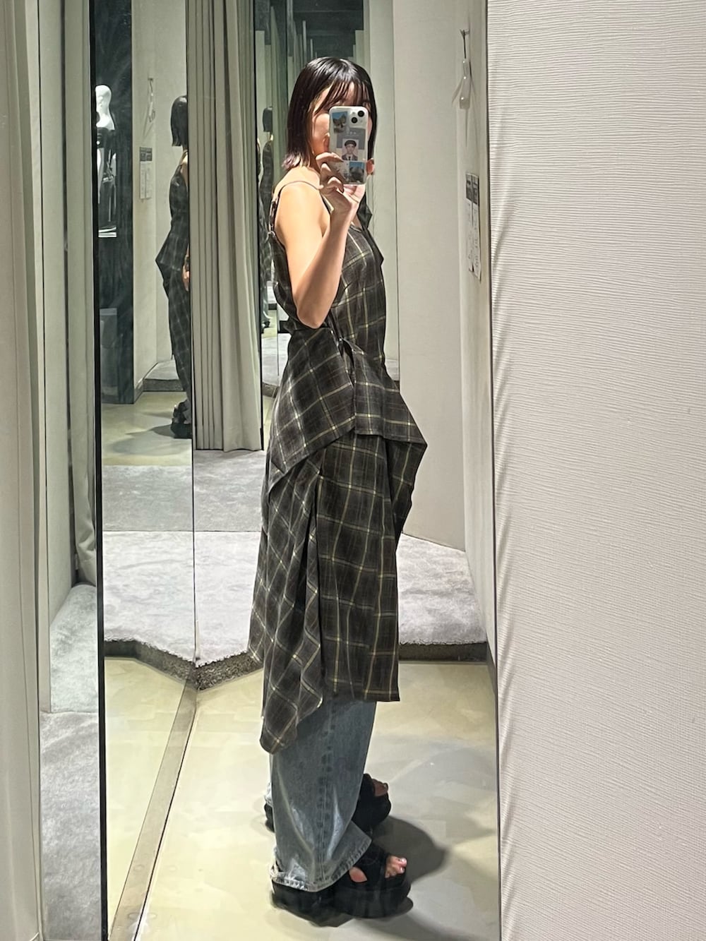 グリーン系のワンピース、ブルー系のデニムパンツ、ブラック系のサンダルを着用したレディースの夏コーディネートの2枚目の写真