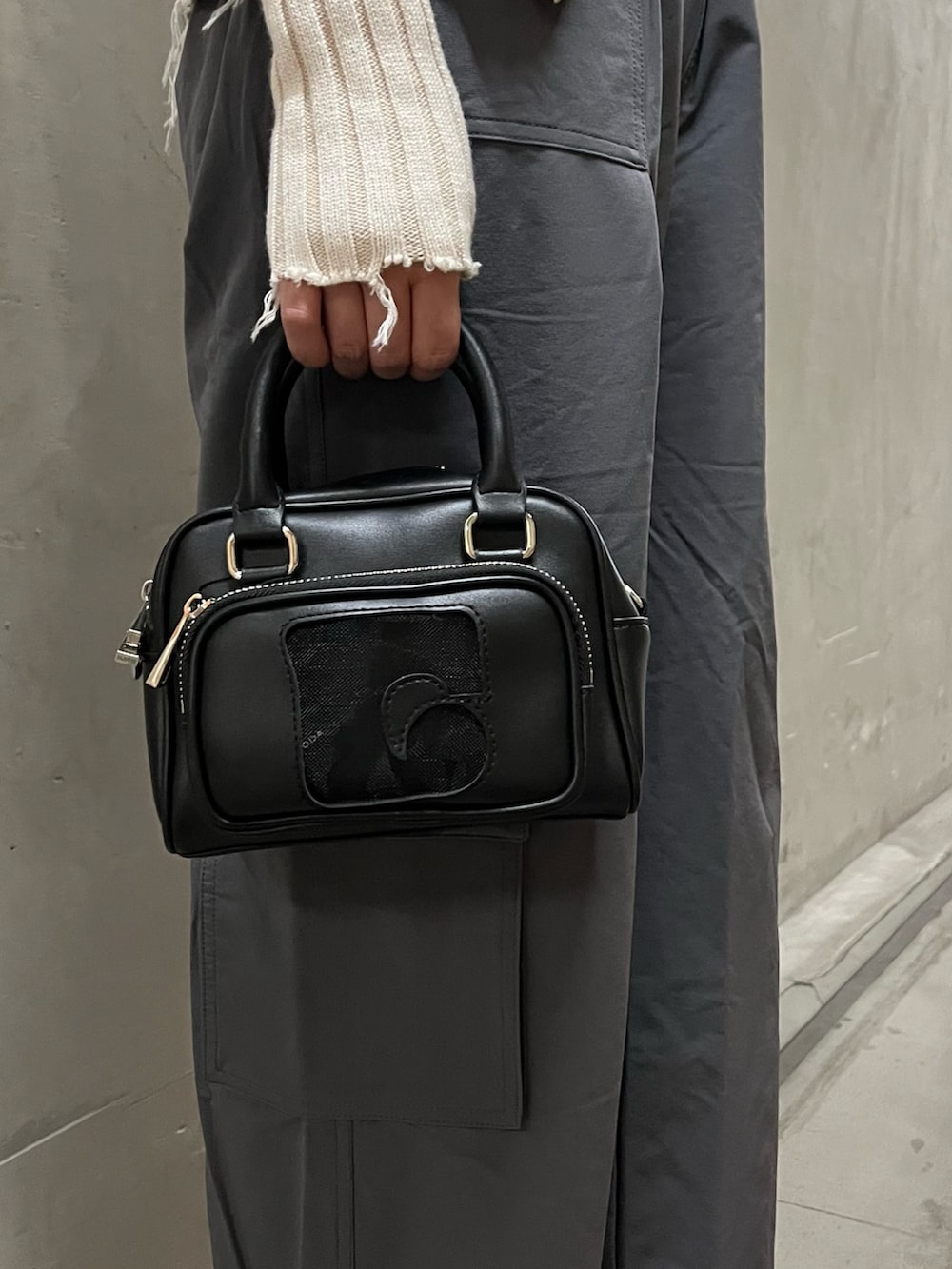 ホワイト系のニット/セーター、グレー系のその他パンツ、ブラック系のハンドバッグを着用したレディースの春コーディネートの6枚目の写真