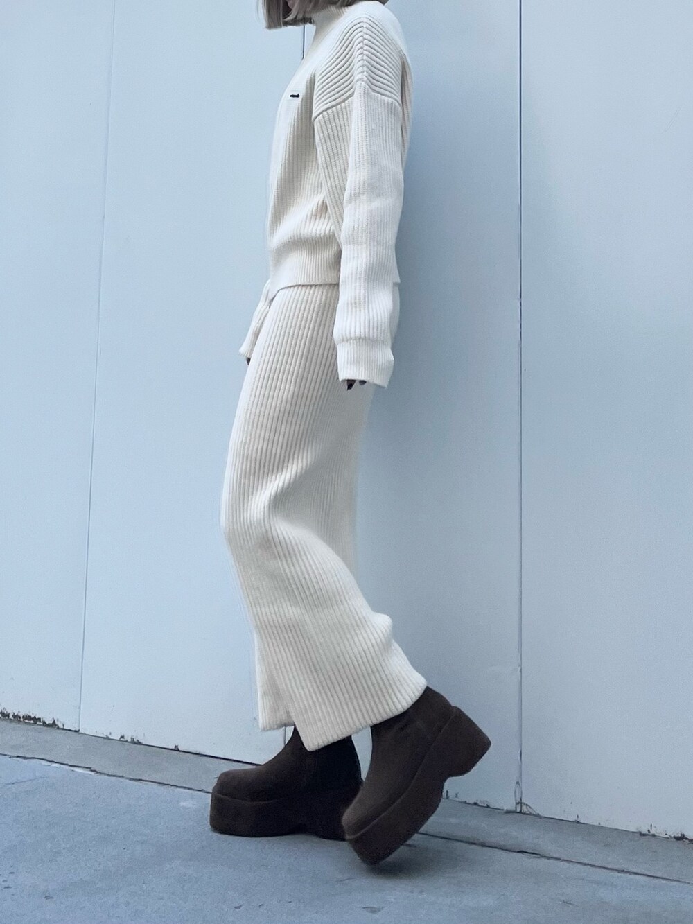 ホワイト系のニット/セーター、ホワイト系のスカート、ブラウン系のブーツを着用したレディースの冬コーディネートの2枚目の写真