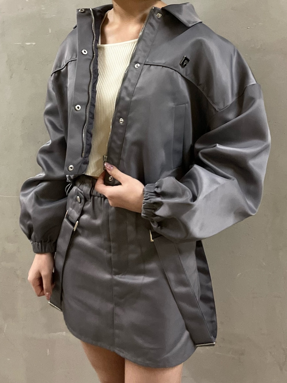 グレー系のブルゾン、グレー系のスカート、ホワイト系のニット/セーターを着用したレディースの冬コーディネートの3枚目の写真