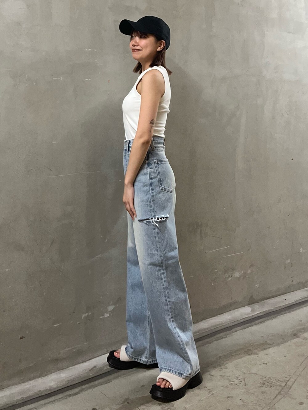 ブルー系のデニムパンツ、ホワイト系のタンクトップ、ホワイト系のサンダルを着用したレディースの夏コーディネートの2枚目の写真