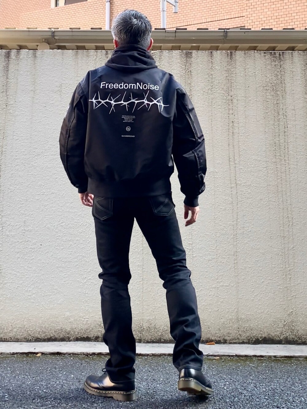 ブラック系のドレスシューズ、ブラック系のデニムパンツ、ブラック系のMA-1を着用したメンズの冬コーディネートの3枚目の写真