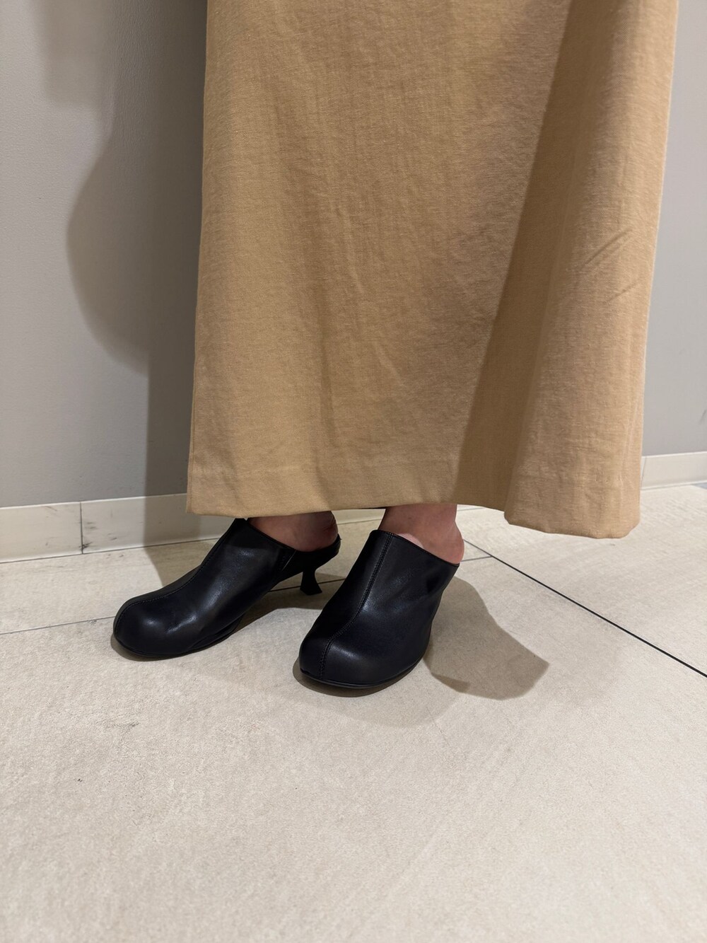 ブルー系のシャツ/ブラウス、ベージュ系のスカート、ホワイト系のニット/セーターを着用したレディースの春コーディネートの6枚目の写真