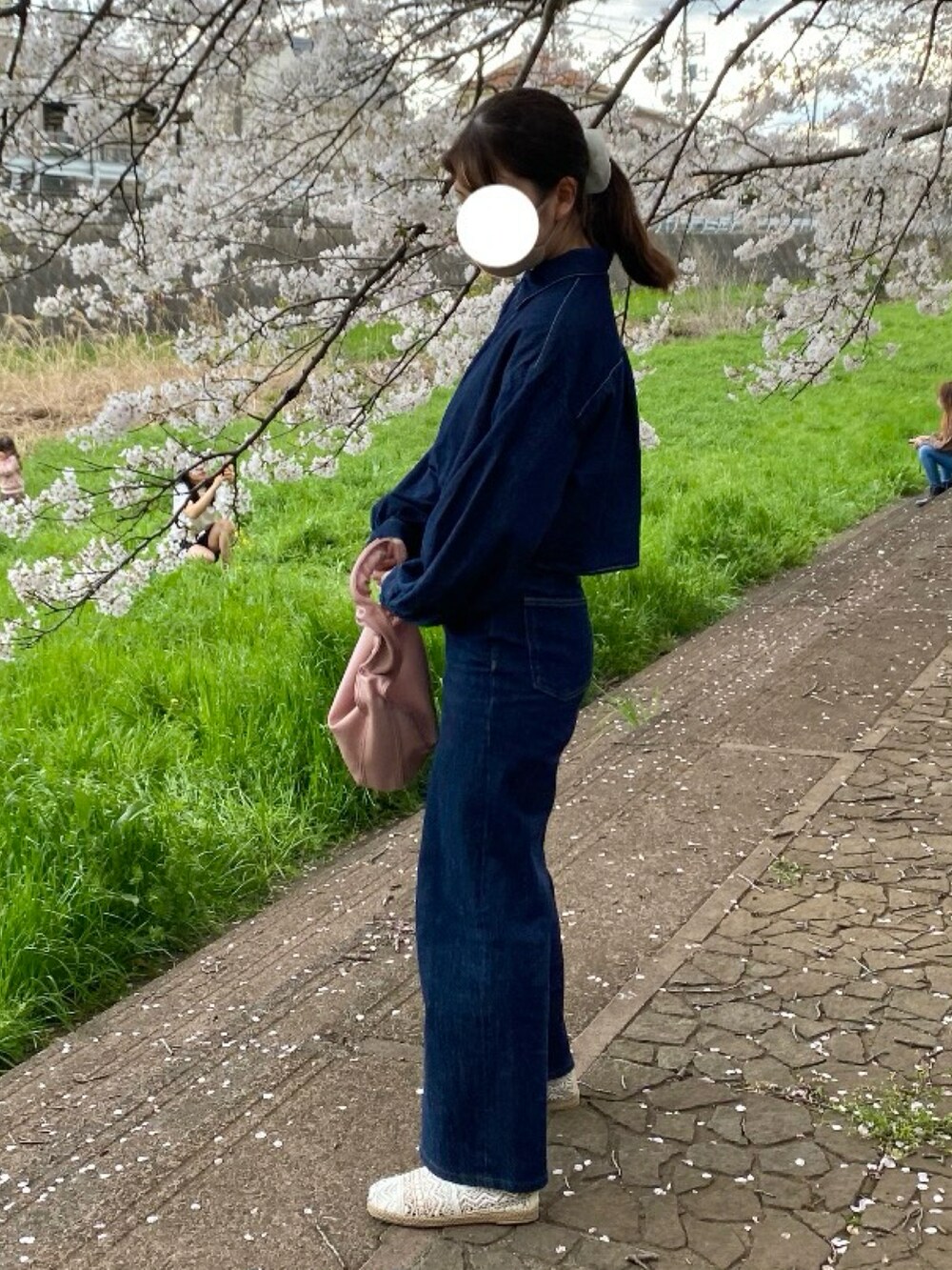 ブルー系のデニムパンツ、ホワイト系のパンプス、ピンク系のハンドバッグを着用したレディースの春コーディネートの2枚目の写真