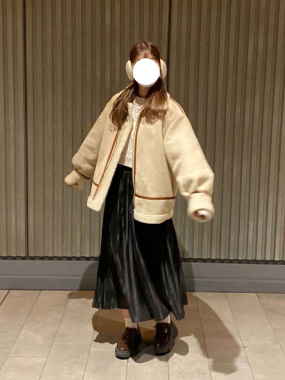 ブラック系のスカート、ブラウン系のドレスシューズ、ホワイト系のムートンコートを着用したレディースの冬コーディネートの2枚目の写真