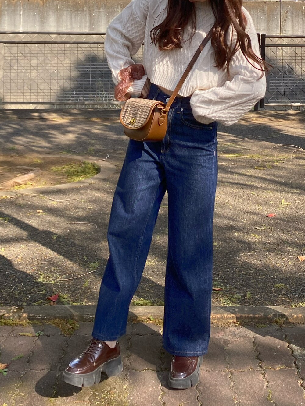 ブラウン系のドレスシューズ、ブルー系のデニムパンツ、ブラウン系のショルダーバッグを着用したレディースの秋コーディネートの2枚目の写真