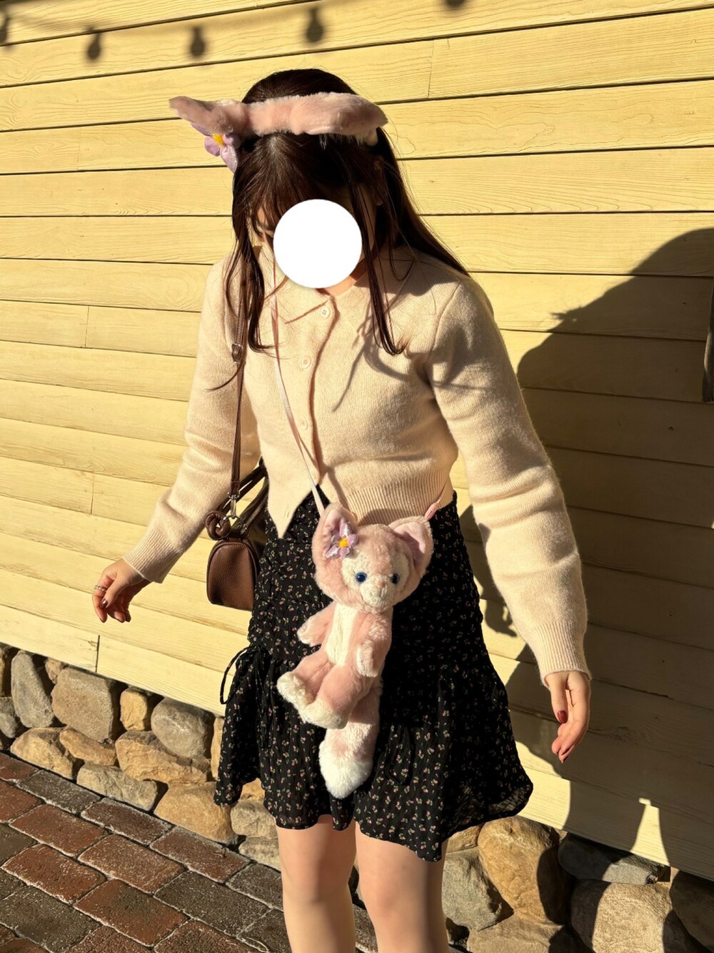 ピンク系のニット/セーター、ブラック系のワンピース、ブラウン系のショルダーバッグを着用したレディースの秋コーディネートの2枚目の写真