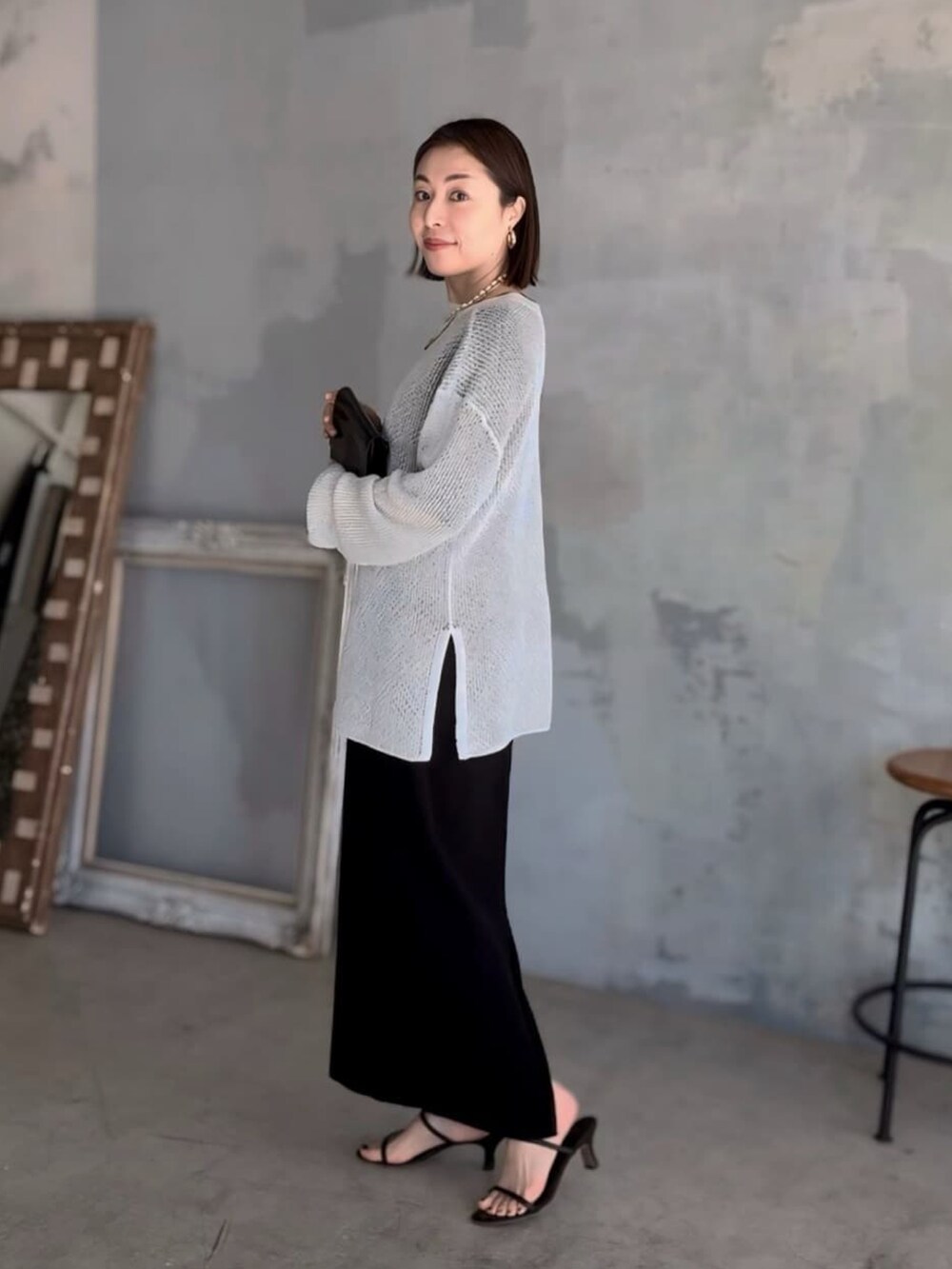 ブラック系のワンピース、ホワイト系のニット/セーター、ブラック系のサンダルを着用したレディースの夏コーディネートの2枚目の写真