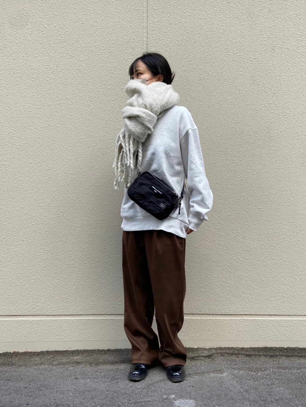 ブラウン系のスラックス、グレー系のスウェット、ブラック系のドレスシューズを着用したレディースの秋コーディネートの2枚目の写真