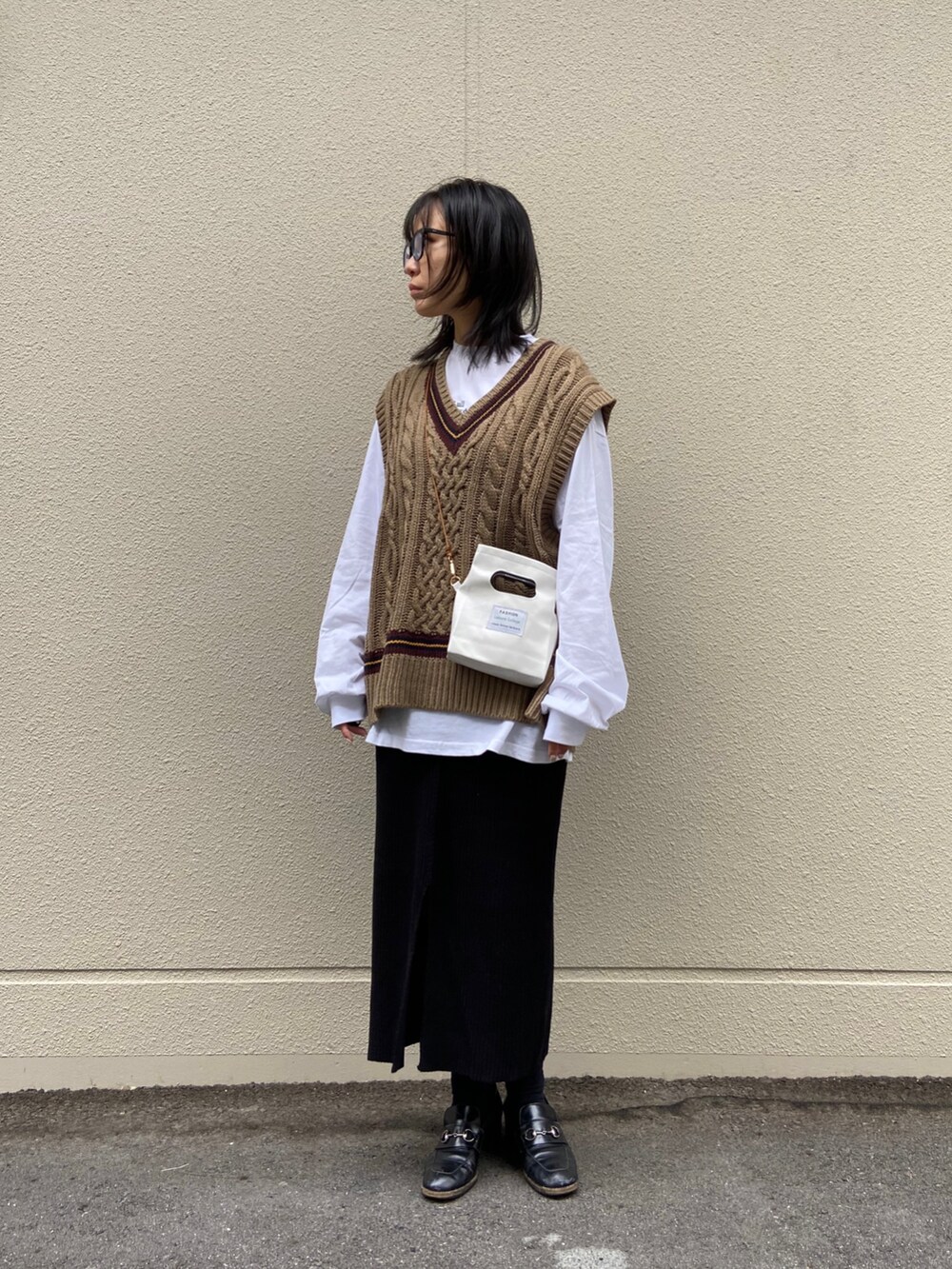 ホワイト系のハンドバッグ、ブラック系のスカート、ホワイト系のTシャツ/カットソーを着用したレディースの秋コーディネートの2枚目の写真