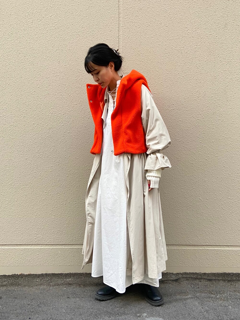 ブラック系のブーツ、ホワイト系のワンピース、ベージュ系のトレンチコートを着用したレディースの秋コーディネートの2枚目の写真