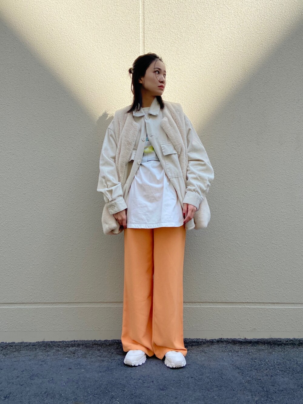 ベージュ系のカバーオール、ホワイト系のスニーカー、オレンジ系のスラックスを着用したレディースの冬コーディネートの2枚目の写真