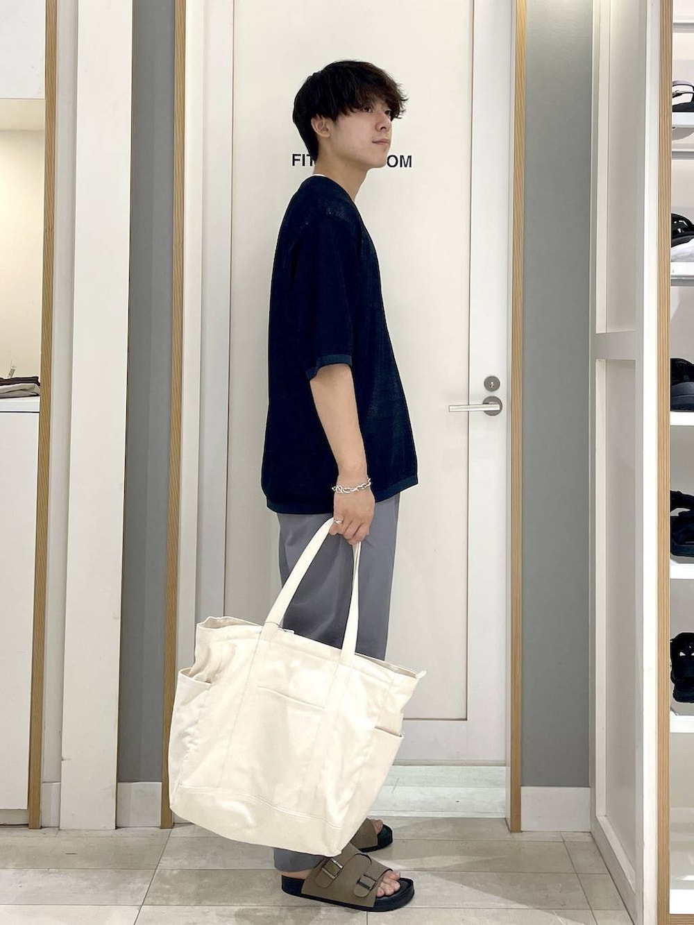 ブルー系のニット/セーター、ホワイト系のトートバッグ、グレー系のその他パンツを着用したメンズの秋コーディネートの5枚目の写真