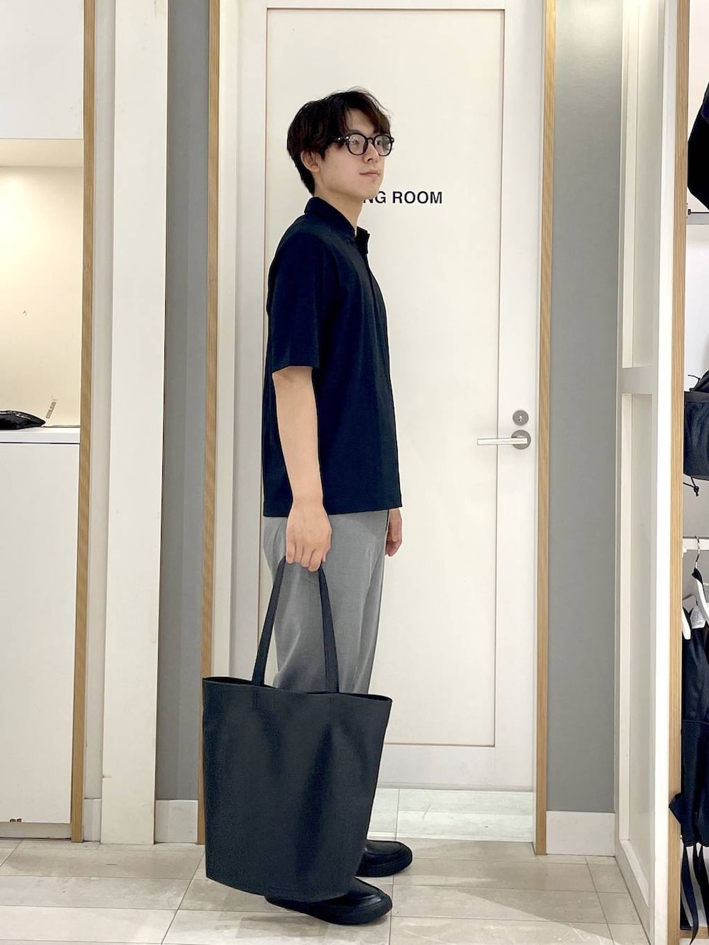 ブラック系のトートバッグ、グレー系のその他シューズ、グレー系のスラックスを着用したメンズの夏コーディネートの4枚目の写真