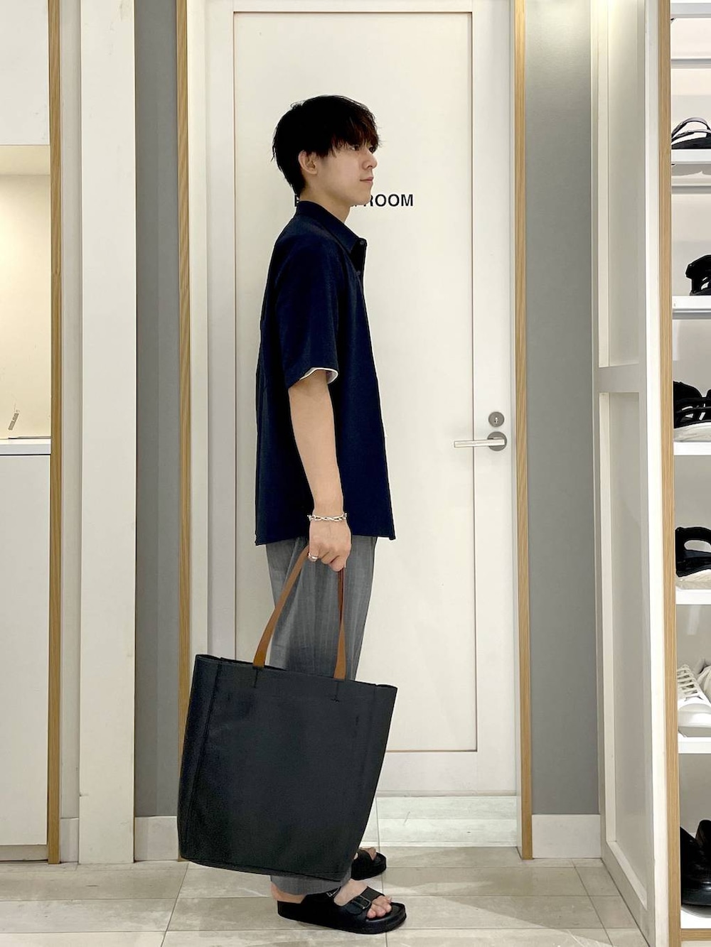 ブラック系のトートバッグ、グレー系のスラックス、ホワイト系のTシャツ/カットソーを着用したメンズの夏コーディネートの3枚目の写真