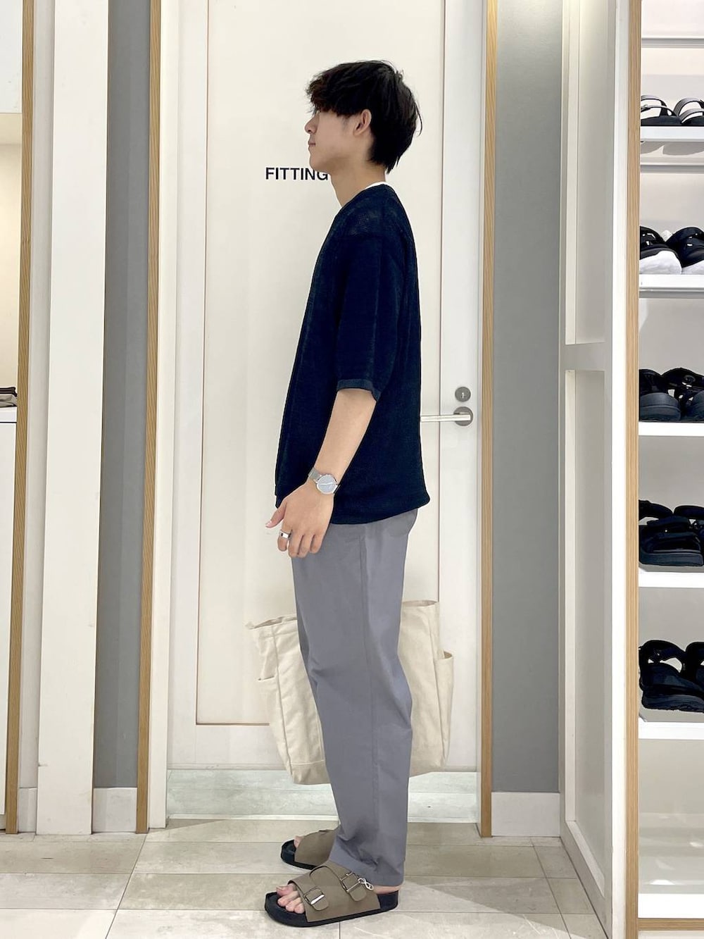 ブルー系のニット/セーター、ホワイト系のトートバッグ、グレー系のその他パンツを着用したメンズの秋コーディネートの4枚目の写真