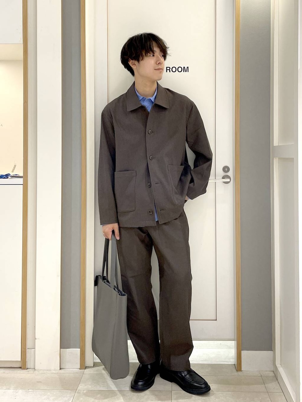 グレー系のトートバッグ、グレー系のその他シューズ、ブルー系のシャツ/ブラウスを着用したメンズの秋コーディネートの3枚目の写真