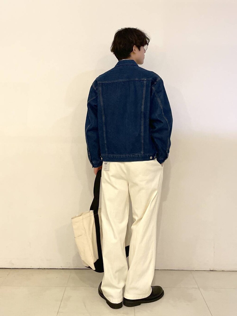 ホワイト系のトートバッグ、ブルー系のデニムジャケット、ホワイト系のその他パンツを着用したメンズの春コーディネートの4枚目の写真