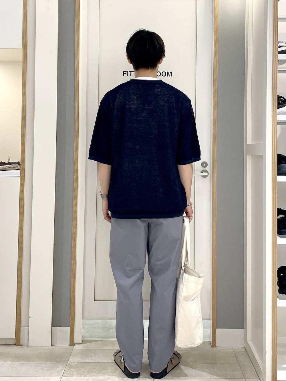 ブルー系のニット/セーター、ホワイト系のトートバッグ、グレー系のその他パンツを着用したメンズの秋コーディネートの6枚目の写真