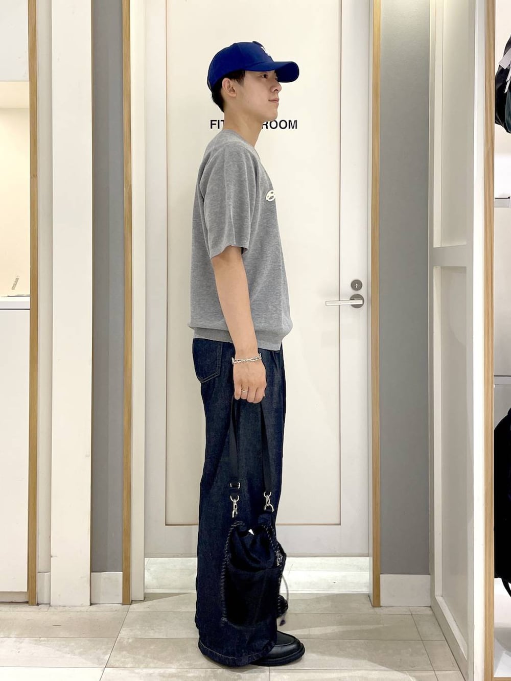 ブラック系のショルダーバッグ、グレー系のニット/セーター、ブルー系のデニムパンツを着用したメンズの夏コーディネートの5枚目の写真