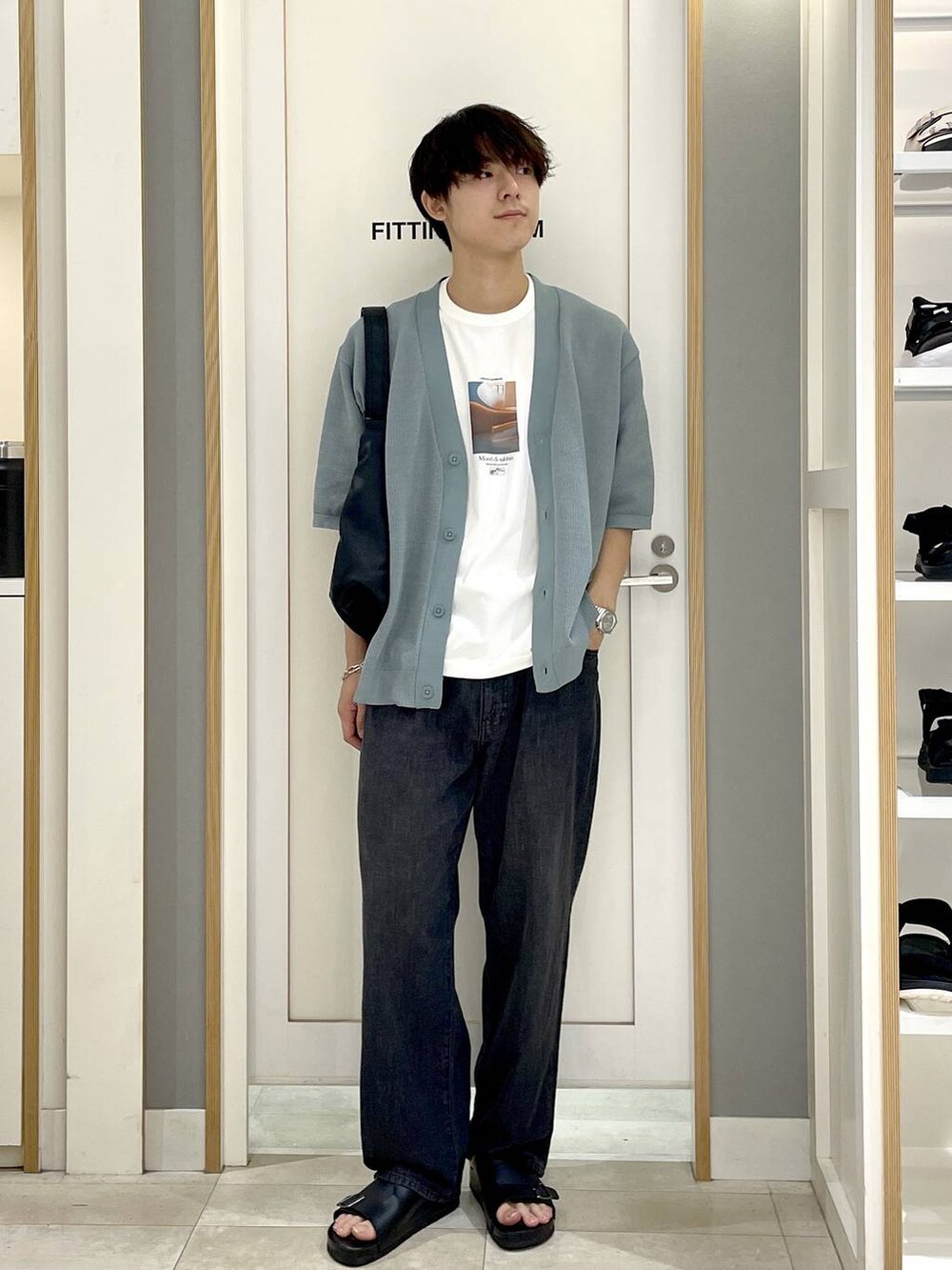 ブラック系のショルダーバッグ、ホワイト系のTシャツ/カットソー、グレー系のデニムパンツを着用したメンズの夏コーディネートの3枚目の写真