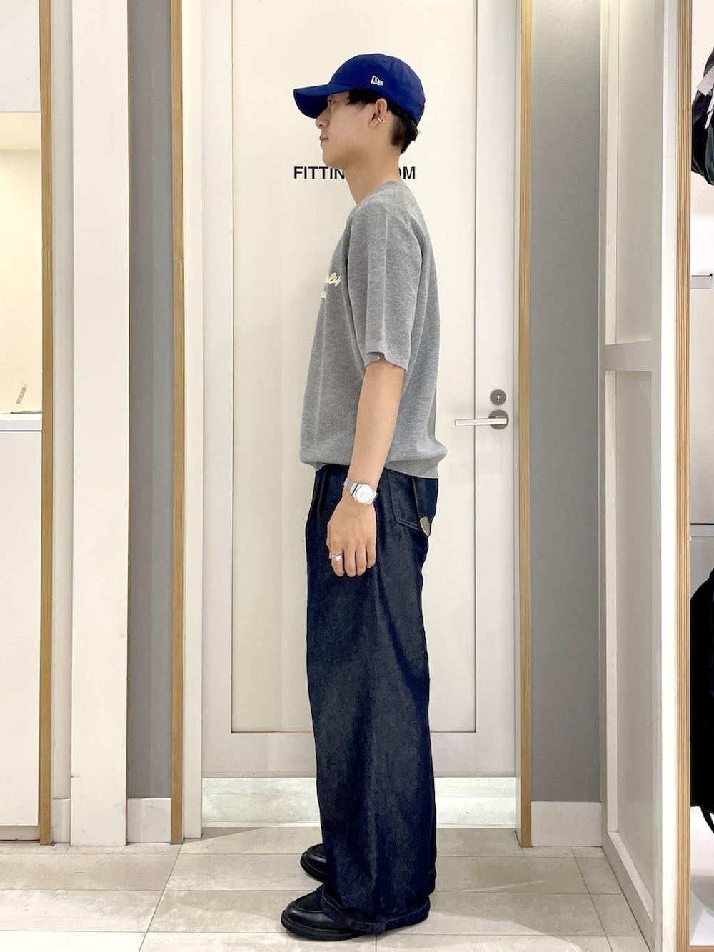 ブラック系のショルダーバッグ、グレー系のニット/セーター、ブルー系のデニムパンツを着用したメンズの夏コーディネートの6枚目の写真